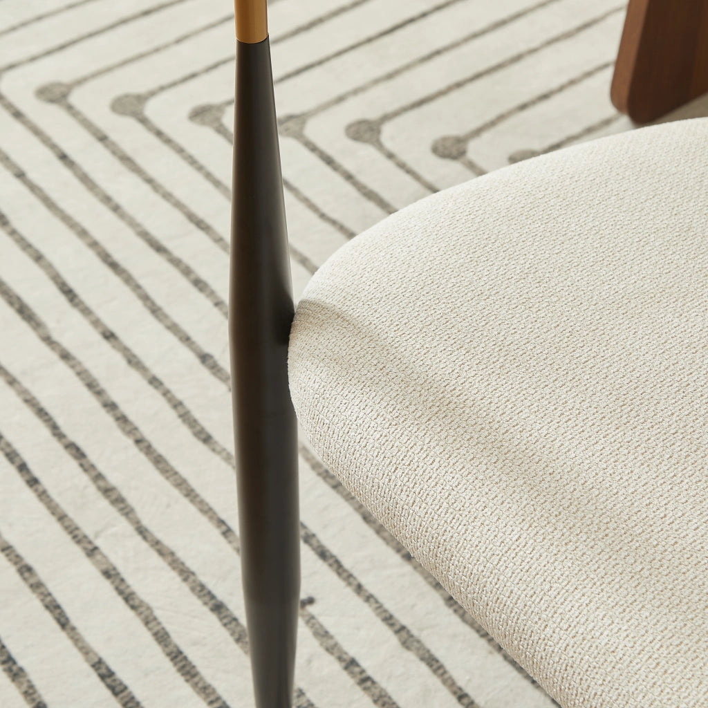 Chaise da pranzo in tessuto con struttura in metallo nero e dettagli oro, cuscini beige, braccioli