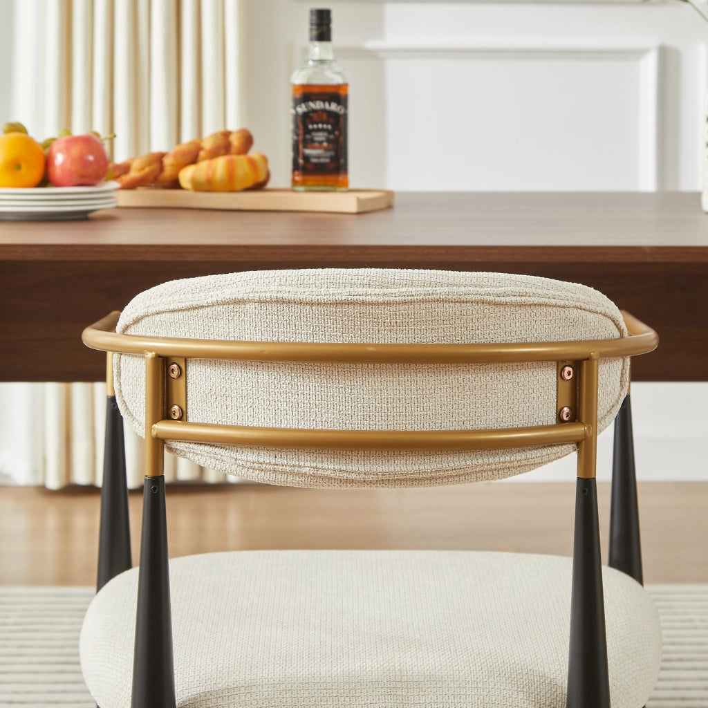 Chaise da pranzo in tessuto con struttura in metallo nero e dettagli oro, cuscini beige, braccioli